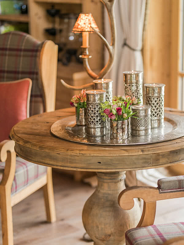 Ein runder Holztisch geschmückt mit Kerzen und Blumen in der Schmiedalm - dem Chalet in Saalbach Hinterglemm