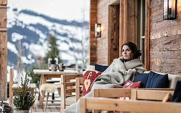 Frau auf Terrasse im Winter Luxus Chalet Schmiedalm Saalbach Hinterglemm